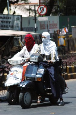 Two wheeler motor bike riders cover their faces with scarf to avoid summer heat at Nagpur, Maharashtra, India  clipart
