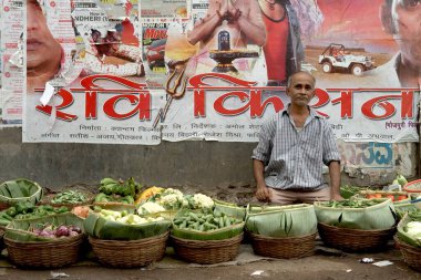 Duvardaki bir Bollywood film posteri Mumbai Bombay, Maharashtra, Hindistan gibi sebze satıcıları için ilginç bir zemin görevi görüyor.