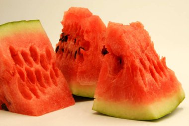 Fruits ; Three quarter pieces of watermelon showing red watery pulp against white background ; Pune; Maharashtra; India clipart