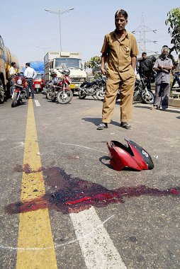 Bombay Mumbai, Maharashtra, Hindistan 'da ekspres yolda kan ve kırık iki tekerlek parçası arayan bir adam.