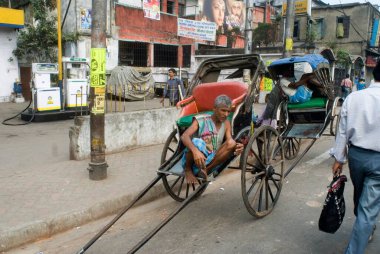 El arabası Rickshaw Puller, Rickshaw 'ında oturuyor. Yolcu bekliyor, Kolkata, Batı Bengal, Hindistan..