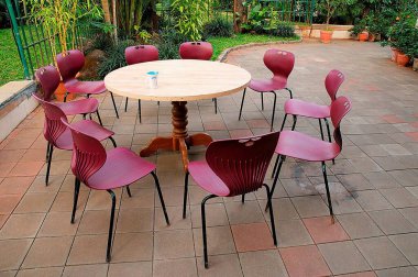 Plastik sandalyeler ahşap masanın etrafında bardak ile tutulur.