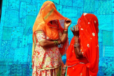 Peçeli iki Rajasthani kadını mavi çarşafa karşı sohbet ediyorlar; Jaisalmer; Rajasthan; Hindistan