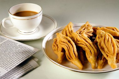 Atıştırmalıklar, beyaz arka planda çay ile Namkeen Maida Karela, Jodhpur, Rajasthan, Hindistan 