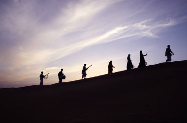 folk Musician and dancers walking on sand dune at Rajasthan India  clipart