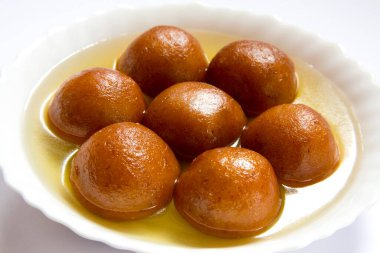 Indian sweet food seven piece of round shape Gulabjamun Bonbon Confectionery with sugar syrup served in plate clipart