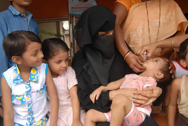 Bombay, Maharashtra, Hindistan 'daki Pulse Polio Drive sırasında çocuk felci aşısı uygulamak için Müslüman bir kadın çocuğunu elinde tutuyor. 