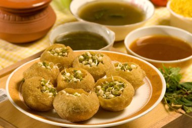 Atıştırmalık, pani puri ve lahana filizli turşu tabakta servis edilir. 