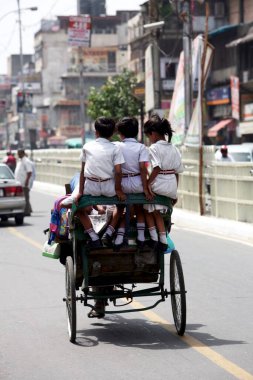 A tricycle rickshaw carrying school children home after the school got over in the Chandni Chowk area of old Delhi, India  clipart