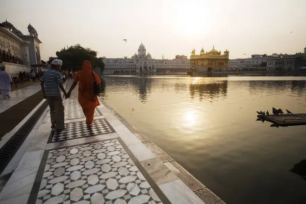 stock image Mother and son walking on the marble design around the holy water pool bathing ghat, Swarn Mandir Golden temple, Amritsar, Punjab, India 