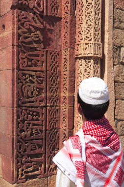 Müslüman çocuk, 1311 yılında inşa edilen kırmızı kumtaşı kulesi, Hint-Müslüman sanatı, Delhi sultanlığı, Delhi, Hindistan UNESCO Dünya Mirası Sitesi 'nde Kur' an 'ın İslami Süslemesini izliyor. 