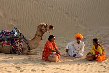 Women and man with camel taking rest in desert of Khuhri, Jaisalmer, Rajasthan, India      clipart