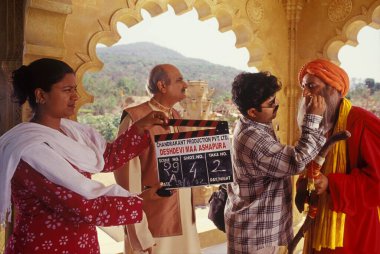 Bir Bollywood film çekimi için son rötuşları yapan bir makyöz ve bir klempçi kız kameranın önünde, film kenti 