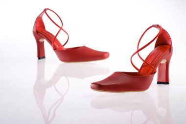 Beyaz arkaplanda yansıması olan kırmızı topuklu ayakkabılar. 