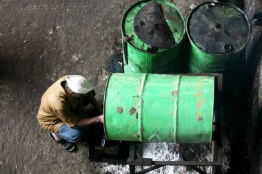 Sangli, Maharashtra, Hindistan 'daki şeker fabrikasında makineler için petrol çıkaran bir işçi. 