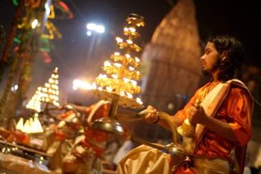 Genç rahip Ganga Pooja 'yı Dasasaswamedh ghat' ta sahneleyecek kutsal Ganga nehrinin kıyısında, Varanasi, Uttar Pradesh, Hindistan 