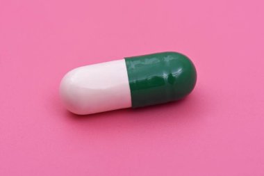 Beyaz yeşil kapsül Pembe arka planda ilaç tableti