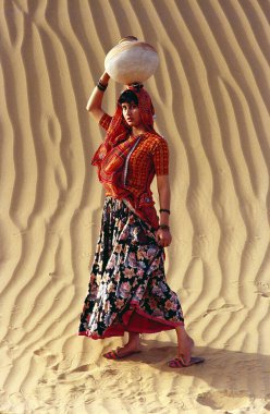 Rajasthani kadını arka planda kum tabakalarının üzerine kil çömlek tutuyor, Bikaner, Rajasthan, Hindistan