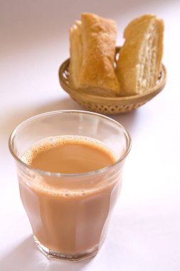 Yiyecek ve içecek konsepti. Toprak çaydanlıkta çay ve beyaz arka planda kamış sepetinde khari bisküvileri.