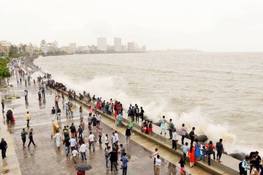 İnsanlar Marine Drive, Mumbai, Maharashtra, Hindistan ve Asya 'da muson deniz dalgalarının tadını çıkarıyorlar.