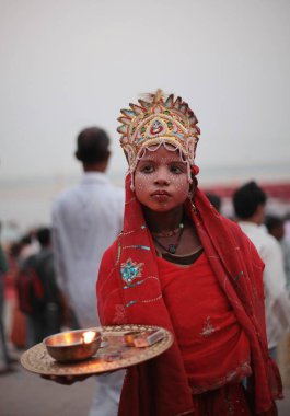 Hindu Tanrısı gibi giyinmiş genç çocuk Ganga Nehri 'nde Uttar Pradesh Hindistan' da sadaka arıyor. 