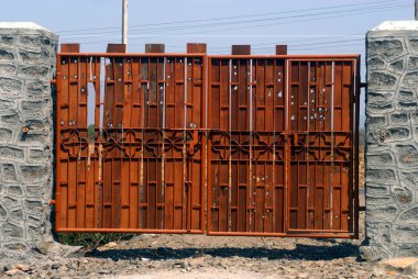 Mild steel pipe gate fixed in rubble masonry pillars,village Khadgoli,district Thane,Maharashtra,India. clipart