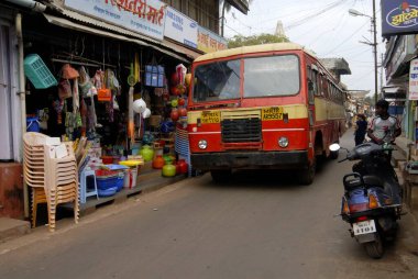 Devlet ulaşım otobüsü, çok dar bir yoldan geçiyor, Malvan 'da, güney Konkan kıyısında, Sindhudurg ilçesinde, Maharashtra, Hindistan' da her iki tarafta da alışveriş kuyruğu var. 