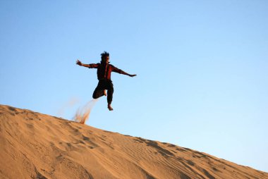 Kum tepesinin üzerinden atlayan çocuk, Khuri Khuhri, Jaisalmer, Rajasthan, Hindistan 