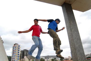 İki genç çocuk Sanpada tren istasyonunda farklı atlama teknikleri uyguluyor; Bombay şimdi Mumbai; Maharashtra; Hindistan