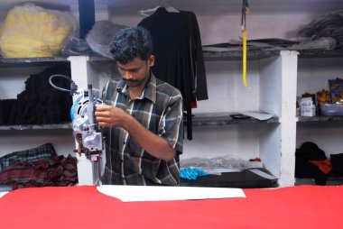 adam çalışıyor, Kumaş bir giyim endüstrisinde kesici kesiyor; Tirupur; Tamil Nadu; Hindistan