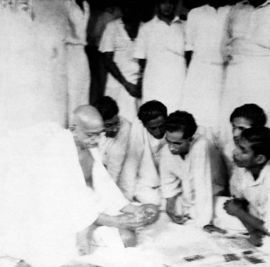 Mahatma Gandhi, Kasım 1946 'da Noakhali Doğu Bengal' i ziyaret ettiği sırada insanlarla konuşuyor ve gazeteleri okuyordu.  