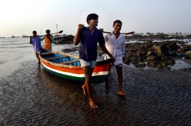 Uttan Sahili 'nde balık tuttuktan sonra kıyıya tekne taşıyan balıkçılar; Bombay yakınları; Maharashtra; Hindistan