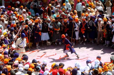 Nihang or Sikh warriors performing stunts with weapon in during Hola Mohalla celebrations at Anandpur sahib in Rupnagar district, Punjab, India    clipart