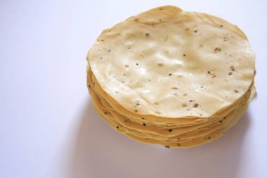 Beyaz zemin üzerinde çeşitli mercimek veya tahıl unlarından yapılmış çiğ papad poppadom