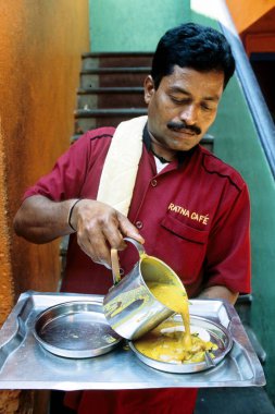 Garson Ratna Cafe 'de Idli' nin üzerine sambar döküyor, Madras Chennai, Tamil Nadu, Hindistan  