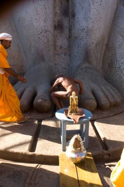 Jain çıplak sadhu, Jain Saint Gomateshwara Lord Bahubali 'nin Mahamastakabhisheka baş vaftiz töreni, Sravanabelagola, Karnataka, Hindistan' daki 58.8 feet monolitik heykelinin önünde eğiliyor. 