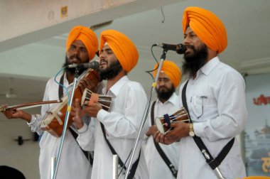 Priests accompanied by musicians in their  continues intonation of the Sri Akhand path ,nonstop reading of the Gurugranth sahib that goes on for over 70 hours Golden temple, Amritsar, Punjab, India  clipart