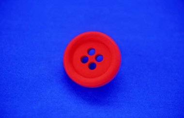 Mavi arkaplanda kırmızı plastik düğme.