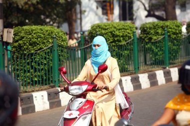 Hintli kız, yüzü tamamen örtülü. Motosikletini Hindistan 'ın başkenti Jharkhand' da sürüyor. 