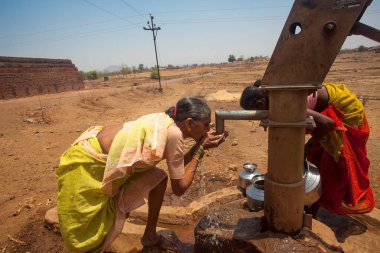 Kabile kadını el pompasından su içiyor, Nandgaon, Atgaon, Maharashtra, Hindistan, Asya  