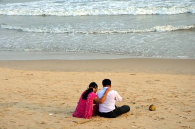 Puri sahilinde oturan çift, Orissa, Hindistan 