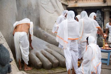 Devotee touching feet of statue of jain deity gomateshvara, Sravanabelagola, Hassan, Karnataka, India  clipart