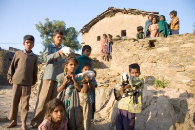 Açık alanda kulübenin dışında duran çocuklar, Bheel kabile topluluğunun kırsal aktivitesi, yarı şehir köyü Dilwara, Udaipur, Rajasthan, Hindistan 