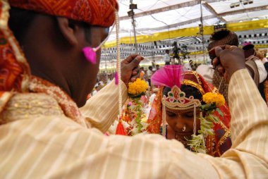 Çiftler, Sant Nirankari Misyonu tarafından Airoli, New Bombay 'da düzenlenen toplu evlilik töreninde evleniyorlar. Şimdi Navi Mumbai, Maharashtra, Hindistan  