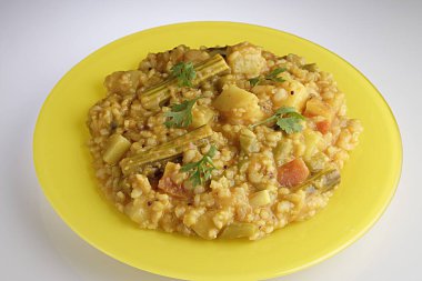 Meal , Bisi bele huli ana south Indian rice and dal lentil with vegetables in yellow plate clipart