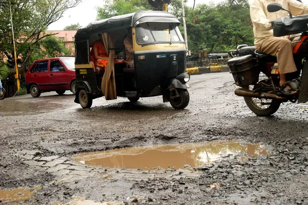 Bombay Mumbai, Maharashtra yakınlarındaki Thane şehrinde trafik sıkışıklığı ve kazalara yol açan ot delikleriyle dolu kötü bir yolda sürücüler var. 