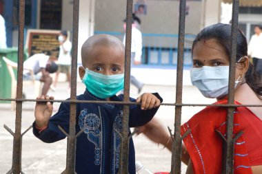 Domuz gribinden, Bombay 'dan, Mumbai' den, Maharashtra 'dan, Hindistan' dan kaçan maskeli anne ve çocuk.   