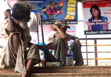 Borivali, Bombay Mumbai, Maharashtra, Hindistan 'da köprüde oturan dilenciler. 