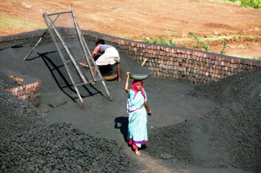 Sangli, Maharashtra, Hindistan 'daki tuğla fabrikasında tuğla yapmak için çamurla harmanlanan tuğla işçileri.