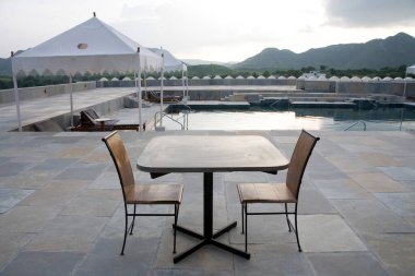 Devigadh, Dilwara Köyü, Udaipur, Rajasthan, Hindistan 'daki zengin saraydaki iki sandalye masası ve yüzme havuzu. 